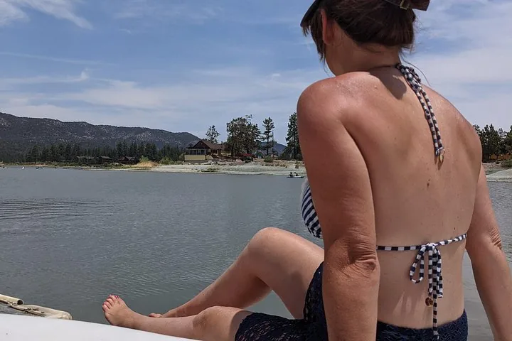Woman sitting on a boat, relaxing and looking towards the lake shore