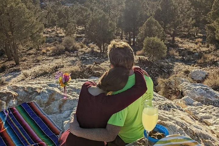 A couple embracing while sitting on a rocky outcrop looking at nature