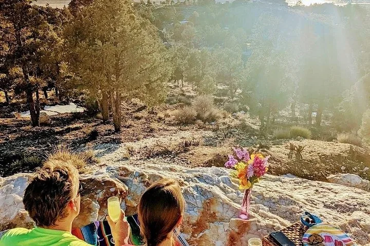 A couple sitting on rocks enjoying the view and drinks in nature