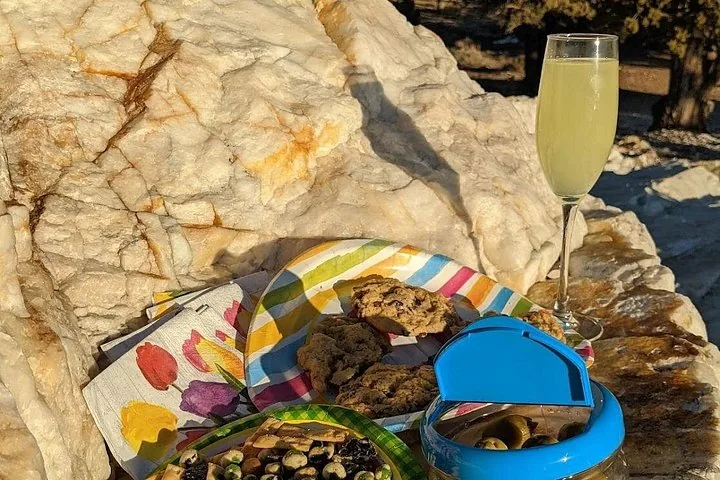 A glass of drink and snacks laid out on rocks during a picnic